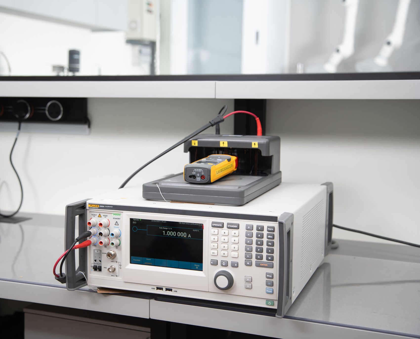 Fluke 5560A reference calibrator and a clamp meter under test on the Unitest bench